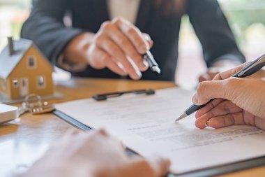 Emlakçı ve müşteri ev, sigorta ya da kredi sözleşmesi imzalıyor.