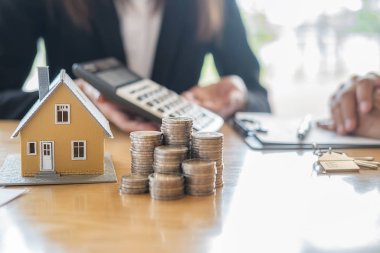 Emlakçı ve müşteriyle ev modeli satın alma, sigorta ya da kredi alma ya da emlak ya da mülkiyet sözleşmesi hakkında tartışıyor.