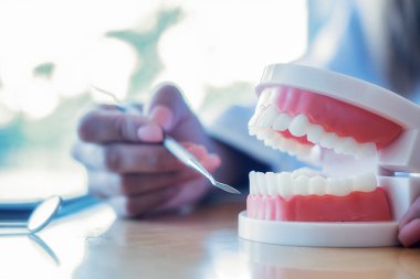 Diş hekimi, diş macunu ve dişçi muayenehanesindeki ayna aletini kullanarak hastaya diş hastalıkları tedavisini gösteriyor ve açıklıyor. Sağlık hizmetleri kavramı.