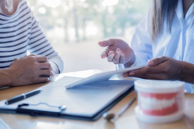 Diş hekimi, diş macunu ve dişçi muayenehanesindeki ayna aletini kullanarak hastaya diş hastalıkları tedavisini gösteriyor ve açıklıyor. Sağlık hizmetleri kavramı.