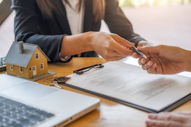 Emlakçı ve müşteri ev, sigorta ya da kredi sözleşmesi imzalıyor.