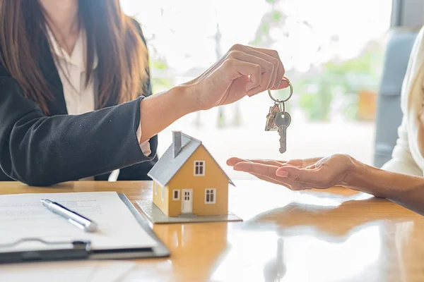 Модель дома с агентом и клиентом обсуждается для контракта на покупку, получить страхование или кредит недвижимости или собственности. — стоковое фото