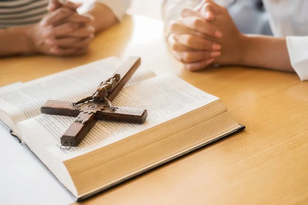 Hıristiyan kadın kutsal İncil ve ahşap haç üzerinde el ele dua ediyor. Kadınlar, daha iyi bir hayat için Tanrı 'ya dua eder ve iyiliğe inanır..