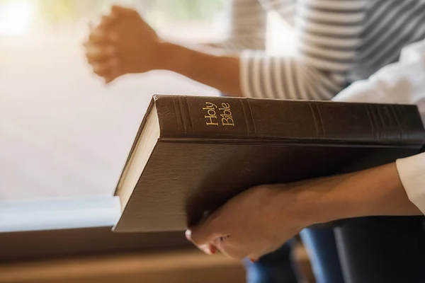 Mujer cristiana orando con las manos juntas en la santa Biblia y la cruz de madera. Mujer rezar para que Dios bendiga a desear tener una vida mejor y creer en la bondad. — Foto de Stock