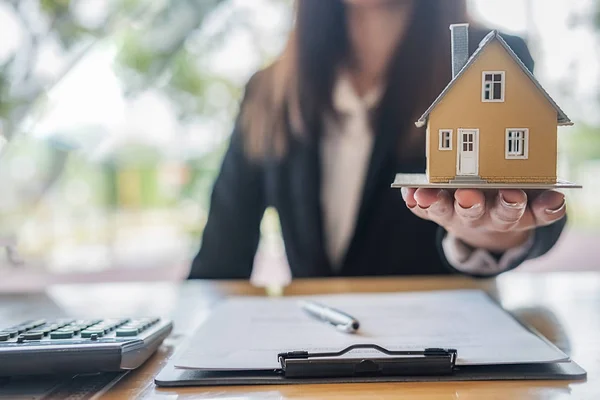 Modelo de casa en la mano del agente que muestra a los clientes a comprar, obtener un seguro, préstamo de bienes raíces o propiedad. —  Fotos de Stock