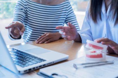 Diş hekimi, diş macunu ve dişçi muayenehanesindeki ayna aletini kullanarak hastaya diş hastalıkları tedavisini gösteriyor ve açıklıyor. Sağlık hizmetleri kavramı.