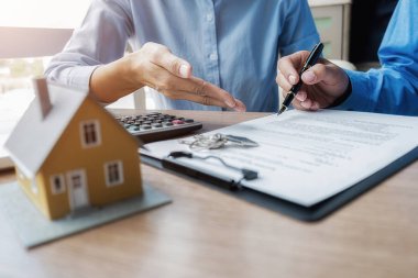 Emlakçı ve müşteriyle ev modeli satın alma, sigorta ya da kredi alma ya da emlak ya da mülkiyet sözleşmesi hakkında tartışıyor.