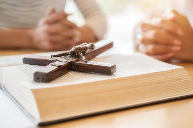 Hıristiyan kadın kutsal İncil ve ahşap haç üzerinde el ele dua ediyor. Kadınlar, daha iyi bir hayat için Tanrı 'ya dua eder ve iyiliğe inanır..