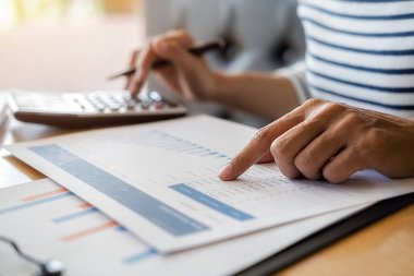 İş adamlarının iş verilerini hesaplamak için hesap makinesi kullanarak yakın plan çekimleri, merkez ofiste muhasebe belgesi.