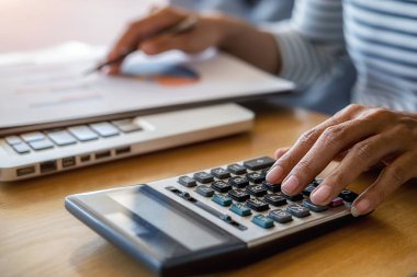 İş adamlarının iş verilerini hesaplamak için hesap makinesi kullanarak yakın plan çekimleri, merkez ofiste muhasebe belgesi.