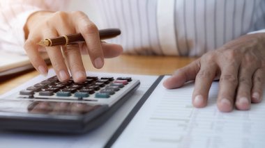 İş adamlarının iş verilerini hesaplamak için hesap makinesi kullanarak yakın plan çekimleri, merkez ofiste muhasebe belgesi.
