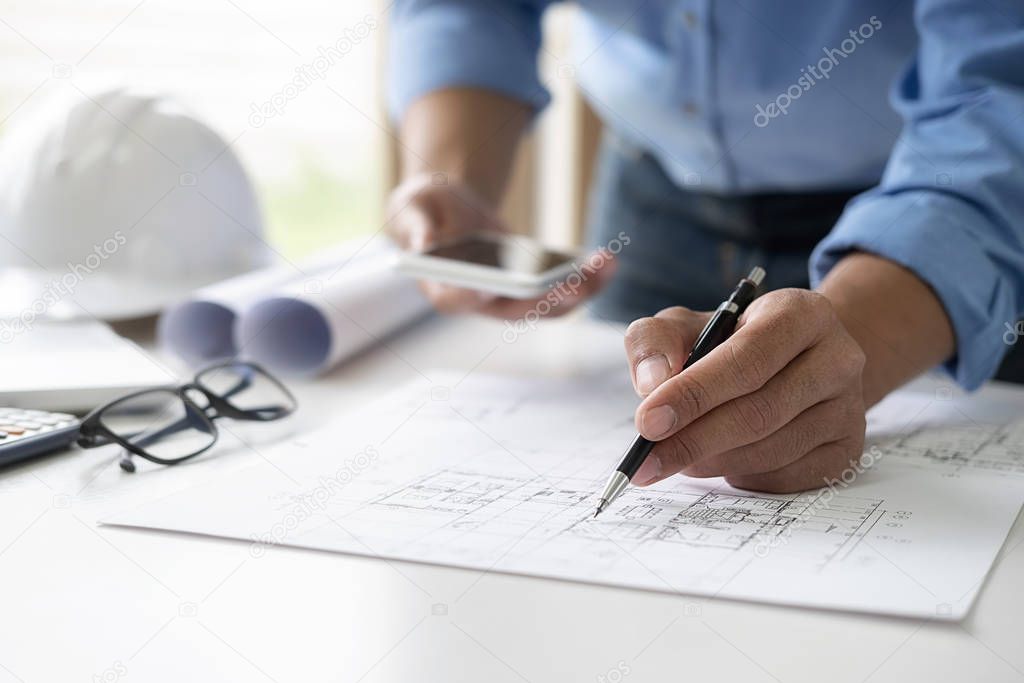 Architect or Engineer working in office with engineering tools, blueprint and building model. Construction concept.