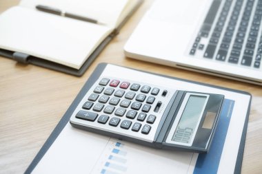 Laptop bilgisayarı, hesap makinesi, ofis malzemeleri, tablolar ve grafikleri olan çağdaş çalışma alanı. İş konsepti.