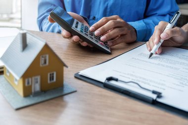 Emlakçı ve müşteriyle ev modeli satın alma, sigorta ya da kredi alma ya da emlak ya da mülkiyet sözleşmesi hakkında tartışıyor.