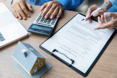 Emlakçı ve müşteriyle ev modeli satın alma, sigorta ya da kredi alma ya da emlak ya da mülkiyet sözleşmesi hakkında tartışıyor.