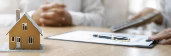 Emlakçı ve müşteriyle ev modeli satın alma, sigorta ya da kredi alma ya da emlak ya da mülkiyet sözleşmesi hakkında tartışıyor.