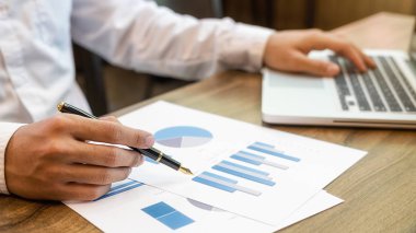 İş adamı başarılı takım çalışmalarının sonuçlarını gösteren çizelge ve grafikleri tartışıyor. İş konsepti.