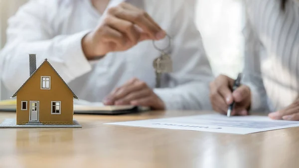 Agente de bienes raíces que tiene una llave y pidiendo al cliente un contrato para comprar, obtener un seguro o préstamo de bienes raíces o propiedades. —  Fotos de Stock