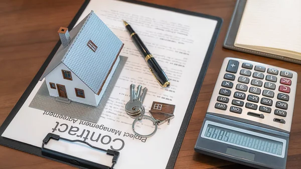 Bureau de l'agent immobilier avec modèle de maison, clé, stylo sur le document contractuel et calculateur pour contrat d'achat, d'obtenir une assurance ou un prêt immobilier ou immobilier . — Photo