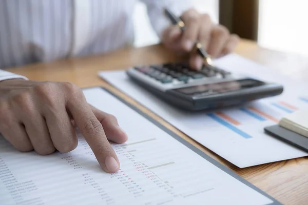 Close-up do homem de negócios mão usando calculadora para calcular os dados de negócios, documento de contabilidade no escritório em casa. — Fotografia de Stock