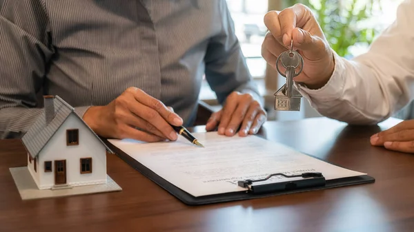 Emlakçı ve müşteriyle ev modeli satın alma, sigorta ya da kredi alma ya da emlak ya da mülkiyet sözleşmesi hakkında tartışıyor.