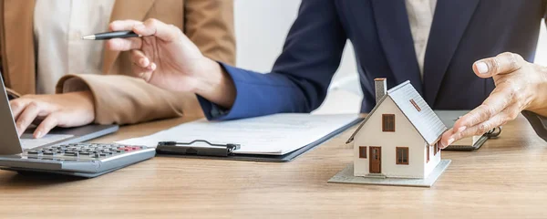 Emlakçı ve müşteriyle ev modeli satın alma, sigorta ya da kredi alma ya da emlak ya da mülkiyet sözleşmesi hakkında tartışıyor.