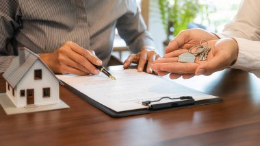 Emlakçı ve müşteriyle ev modeli satın alma, sigorta ya da kredi alma ya da emlak ya da mülkiyet sözleşmesi hakkında tartışıyor.