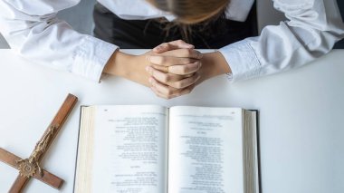 Hristiyan kadın kutsal İncil ve ahşap haç üzerinde dua ediyor. Kadınlar, daha iyi bir hayat için Tanrı 'ya dua eder ve iyiliğe inanır..