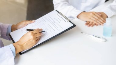 Doktor danışman hasta, Coronavirus hastalığı teşhisi üzerinde çalışırken klinikte ya da hastane ofisinde reçeteli bilgi belgesi üzerinde çalışıyor. Tıbbi ve Sağlık Konsepti.