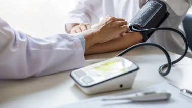 Klinikte ya da hastane ofisinde hastanın tansiyonunu ölçen bir doktor. Tıbbi ve Sağlık Konsepti.