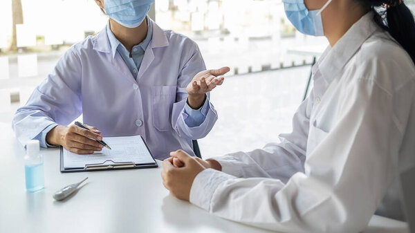 Врач консультирует пациента, работает над диагностическим обследованием коронавирусной болезни при записи рецепта в клинике или больничном кабинете. Медицинская концепция.