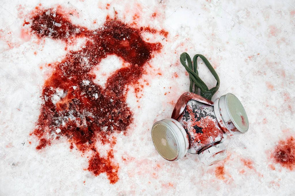 Personal protective equipment gas mask lies in the snow in a puddle of blood