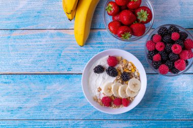 Müsli yoğurt ve ahşap masada meyve..