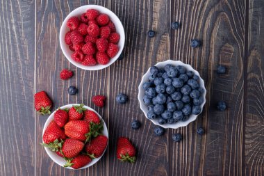 Böğürtlenler, tahta bir masada yaz meyveleri. Yaban mersinleri, çilekler, masada ahududular..