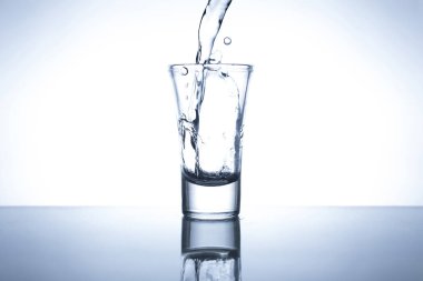 Camdan yakından bakınca, cam sehpadaki bardağa biraz alkol dökülmüş ve beyaz arka plan...