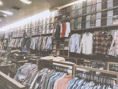 Giysi mağazası, raflardaki farklı boyut ve renkler ve raflarda asılı eski ve canlı tonlarda.