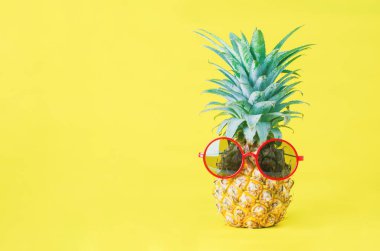 Sarı arka planda kırmızı güneş gözlüklü ananas - yaz arkaplanı
