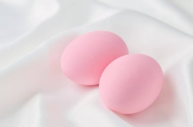Beyaz saten tekstil arka planda pembe pastel paskalya yumurtalarını yakın plan, Paskalya arkaplanı.
