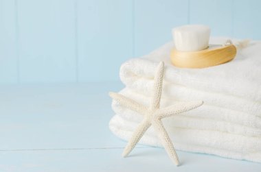 Mavi ahşap arka planda yüz temizleme fırçası olan deniz yıldızı ve beyaz havluları kapatın.