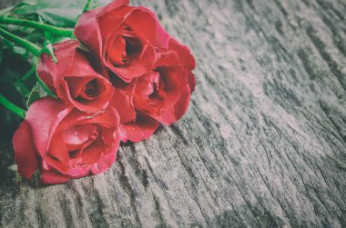 Eski ahşap arka plandaki kırmızı gül buketini kapatır mısın?