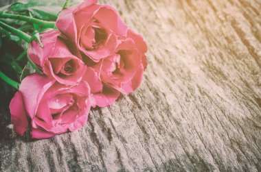 Eski ahşap arka plandaki kırmızı gül buketini kapatır mısın?