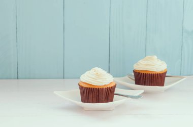 Beyaz tabakta vanilyalı kek, beyaz ve mavi ahşap arka planda, yumuşak klasik tonda.