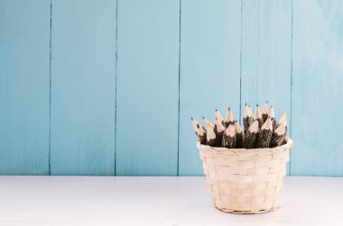 Beyaz ve mavi ahşap arka planda dokuma sepetinde renkli ahşap kalem