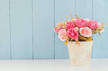 Pastel Yapay Pembe Düğün Gelini Çiçek saksısı beyaz ve mavi ahşap arka planda yumuşak vintage tonda