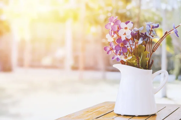 人工紫と白の花は ヴィンテージと日光トーンと木製のテーブルの上に白い花瓶で — ストック写真