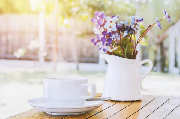 白コーヒーカップと花の花瓶をヴィンテージと日光トーンで木製のテーブルの上に閉じます — ストック写真