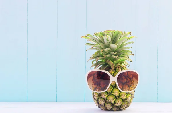 Funny Pineapple with white sunglasses on blue wooden background, Tropical and summer fruit