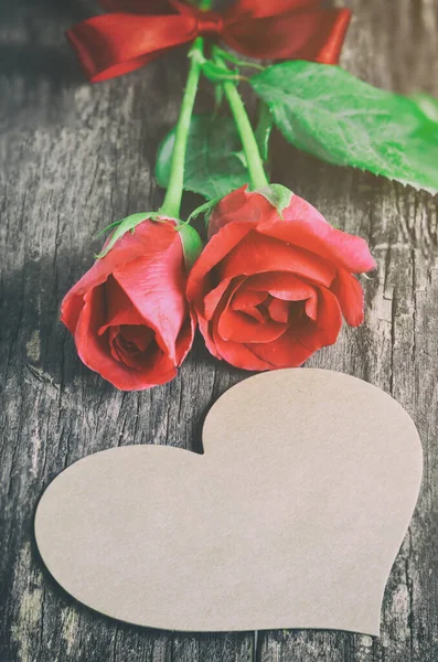 ハート型のブランクブラウングリーティングカードと ヴィンテージとヴィネットトーンの木の背景にある赤いバラの花の花束 バレンタインのバラ — ストック写真
