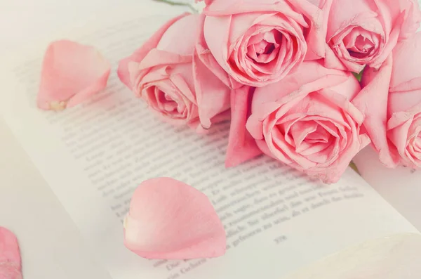 Close up of pink pastel rose flower bouquet with pink petal rose on opened book with vintage tone, Vintage roses