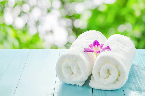 Close up of white towels roll with purple orchid flower on blue wooden table isolate on white background with clipping path